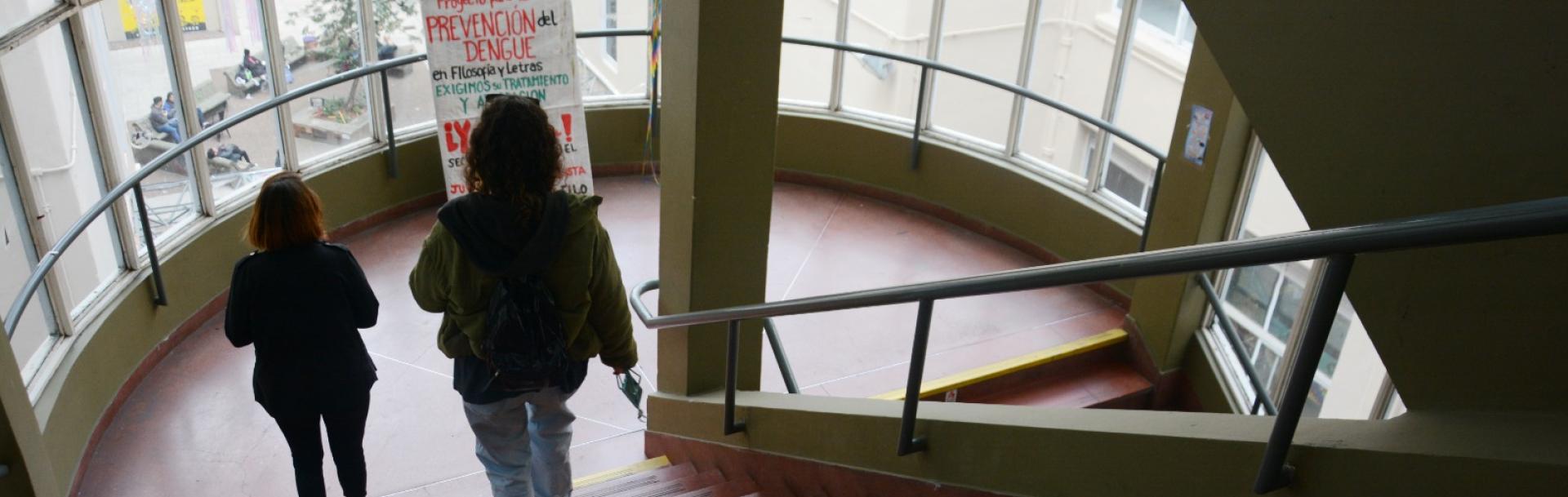 Dos estudiantes bajan las escaleras de la sede Puan. 